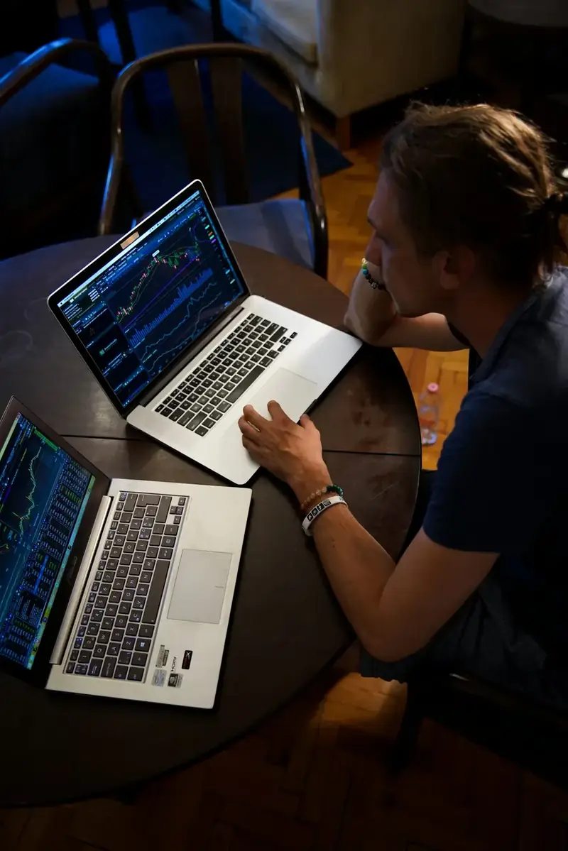 Trader studying charts on two laptops